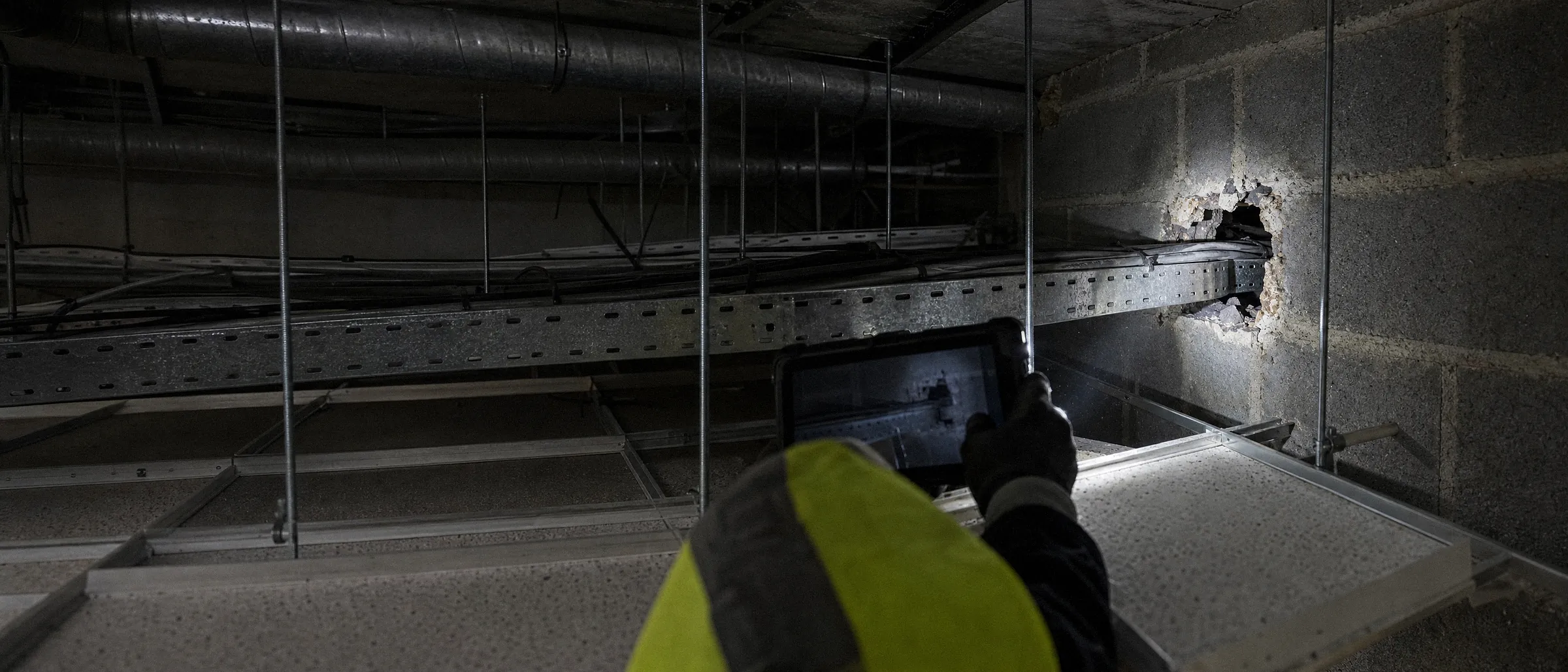 Surveyor photographing an unsealed hole around a cable tray in a compartment wall