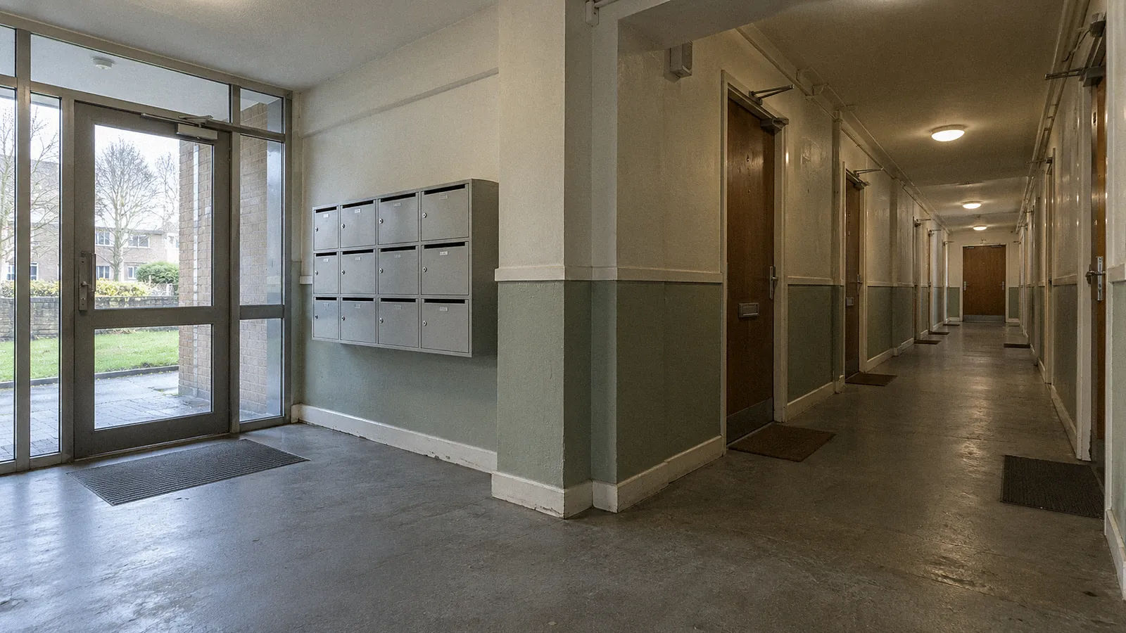 Communal entrance hall of a block of flats with flat entrance doors and an escape route