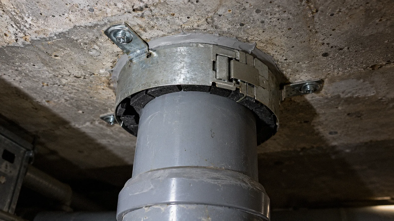 Plastic soil pipe through a concrete floor fitted with an intumescent fire collar